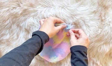 A person stitching a fabric circle.