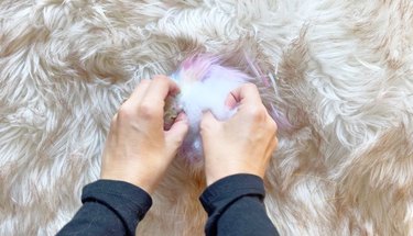 A person filling a fur pom pom with Poly-fil