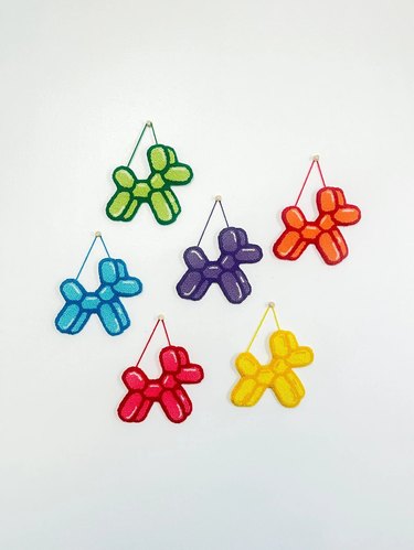 Six colorful balloon-dog wall hangings made with punch needle technique
