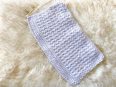 A crochet rectangle featuring one row of double crochet stitches, 14 rows of criss-cross stitches, and four rows of double crochet stitches.