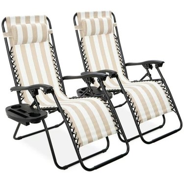 Set of two tan and white striped zero gravity chairs with detachable holding trays for your phone, drink, etc.