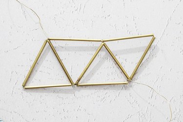 Wires twisted through metal tubes to create four adjoining triangles