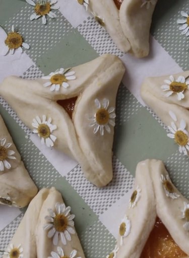 Folded triangular pastries topped with dried white and yellow flowers