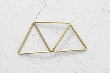 Wires twisted through metal tubes to create three adjoining triangles