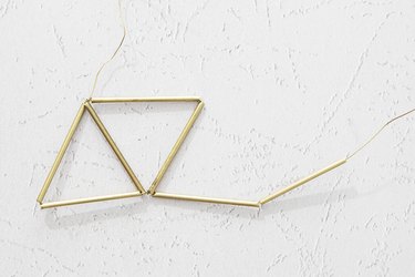 Wires twisted through metal tubes to create two triangles, with a third triangle being formed.