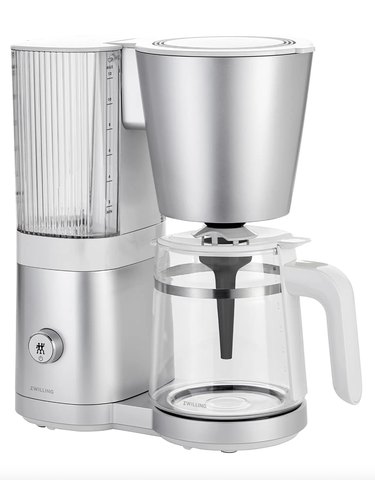 Silver drip coffee maker with carafe and fluted plastic water tank.