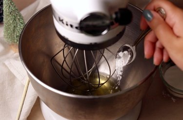 Adding cream of tartar to stand mixer bowl with egg whites.