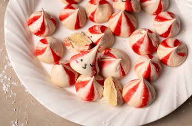 Peppermint swirl meringues with cute faces on a white plate.