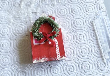 A red wooden house with a large Christmas wreath in the center