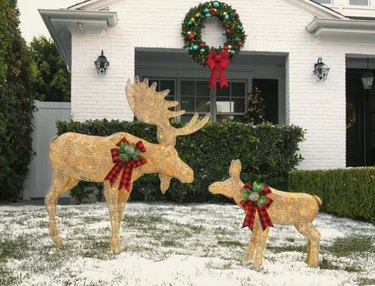 Gold adult bull moose and baby with LED lights and buffalo check bows with faux greenery and a pinecone in the middle.