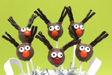 Six cake pops with candy faces and licorice antlers