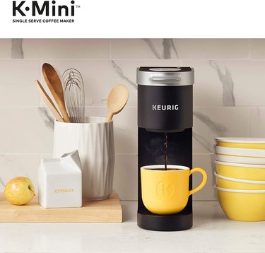 Black Keurig K-Mini coffee maker on kitchen countertop with bright yellow coffee mug.