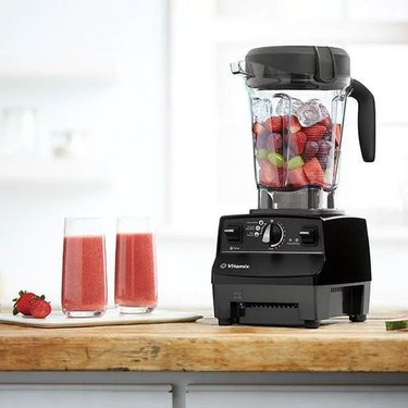 Vitamix 6500 blender shown with fruit and ice in its container, sitting next to two smoothies.