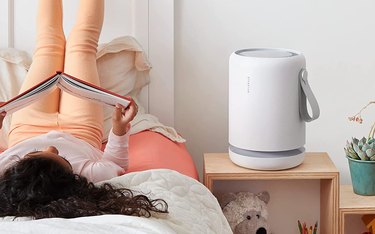 Small Mokekule air purifier in white on bedside table next to young girl reading.