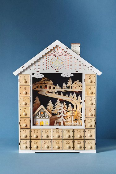 Wooden reusable advent calendar with a village scene, made of plywood with a light-up feature.