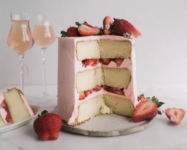 A three-layer cake with pink frosting and strawberries