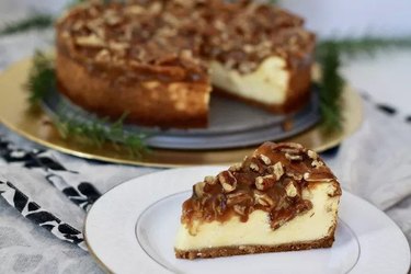 A slice of cheesecake covered with pecan pie topping
