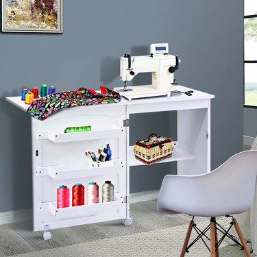 Sewing table on wheels with three shelves on the left side and an optional middle shelf where the chair slides into.
