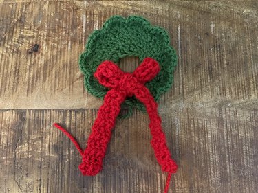 A green crochet wreath with a red bow
