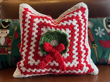 A red and white striped pillow with a green wreath in the center