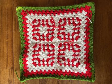 Four red and white crochet granny squares with a green and red border