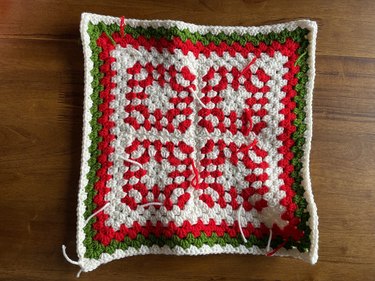 Four red and white granny squares with a red, green and white crochet border