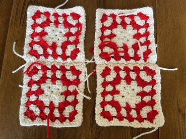 Four red and white crochet granny squares stitched together to create two rectangle pieces