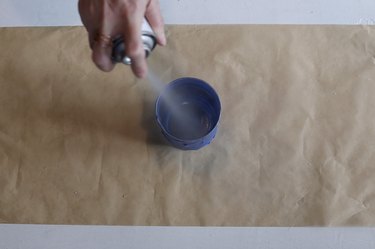 spraying mirror spray paint inside glass jar