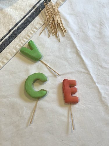 Colorful alphabet letters with toothpicks for cake decorating.