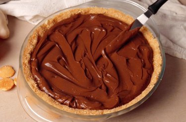 Using an offset spatula to spread chocolate cream pie filling.