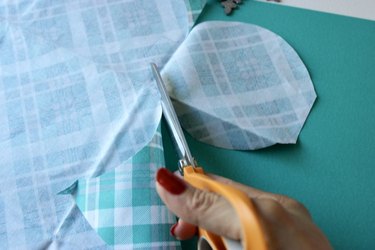 Scissors cutting circle out of plaid blue fabric