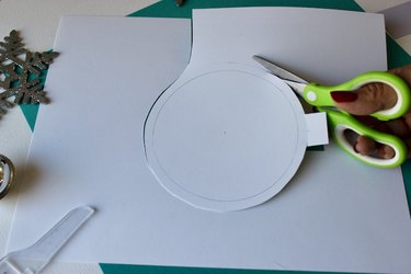 Scissors cutting a circle from white card stock