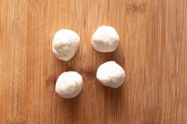 Balls of biscuit dough on a wooden cutting board