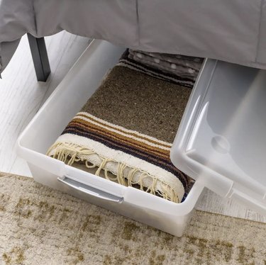 Clear plastic storage bin under a bed