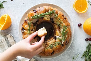 Hand dipping piece of monkey bread in chocolate sauce