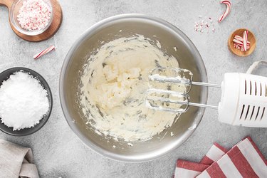 Cream cheese in a bowl being whipped by a mixer.