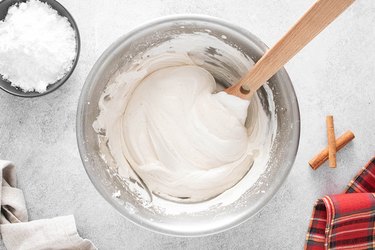 Whipped topping being folded with a wooden spoon.