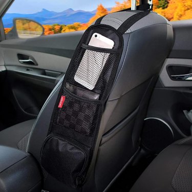 Black organizer on side of front car seat holding phone