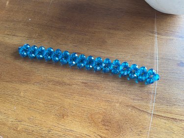 A row of blue beads woven together with fishing wire