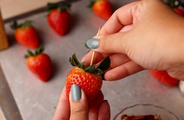 Skewering a strawberry with a toothpick.