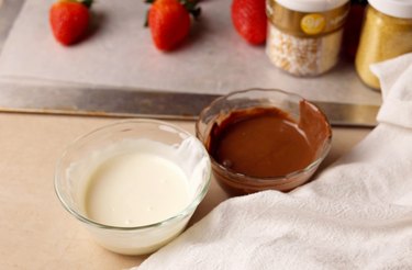 Two bowls of melted chocolate for dipping strawberries.