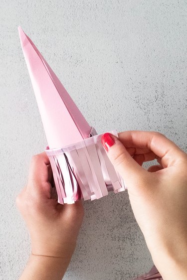 Hot glue pink tinsel fringe around paper cone