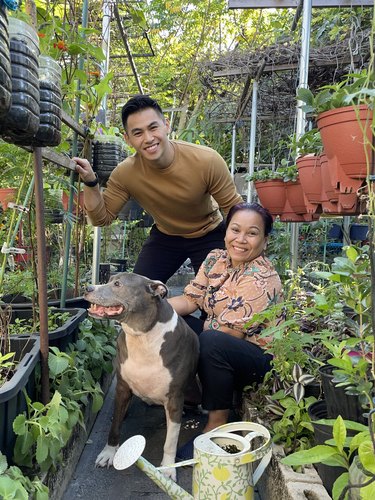 Thong La and Judy Bao pose with Diamond the dog, surrounded by plants in pots