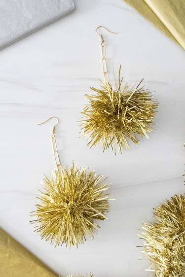 Gold tinsel pom pom earrings on a white background