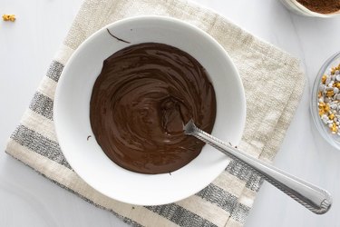 Melted chocolate for hot cocoa bombs in a white bowl