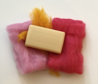 Bar of soap on pink and yellow wool roving