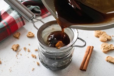 Pouring gingerbread syrup through a strainer and into a jar