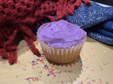 A cupcake with lavender purple frosting, purple shimmer and glitter.