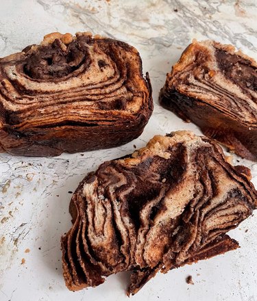 Three pieces of vegan chocolate babka with brown swirls.