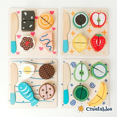 Four wood cutting board toys with food: fruits, veggies, proteins and desserts.